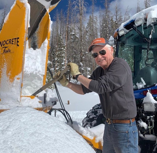 Eno in Vagabond in winter clearing the snow from a plow on a sunny day.